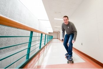 man on a skateboard in an academic building hallway