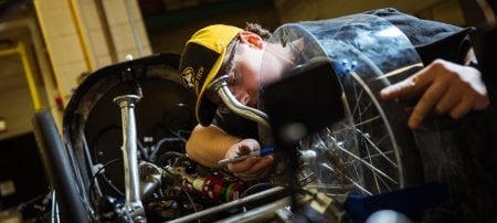 A member of Michigan Tech's Supermileage Systems Enterprise works on the team's vehicle in a lab at the university