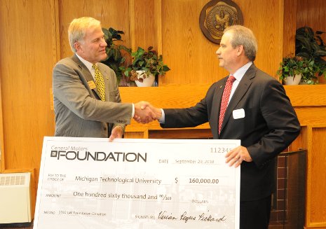 Terry Woychowski, at right, a Tech alumnus and vice president of General Motors, presents President Glenn Mroz with a contribution from the GM Foundation.