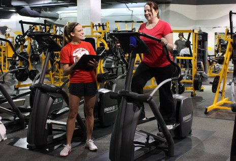 Crystal Verran works out on an elliptical machine under the watchful eye of personal trainer and kinesiology student Rosanna Chopp.