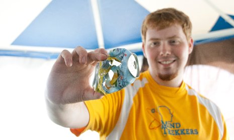 A Michigan Tech Mind Trekkers student volunteer holds a soda can ripped apart by a pingpong ball.