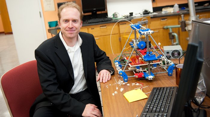 Joshua Pearce with printer Joshua Pearce, organizer of the 3D Printers for Peace Contest, with one of the 3D printers used for research and teaching in his lab.