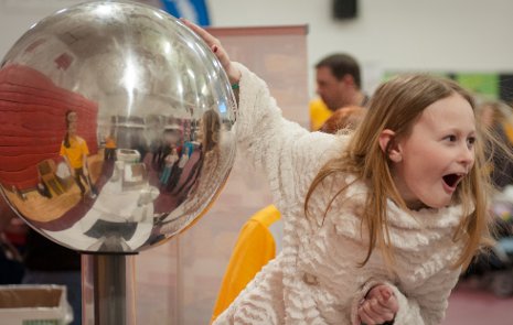 A startling experience: Touching a Van de Graaff generator makes a girl's hair stand on end.
