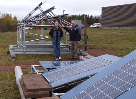 Solar energy scientist Joshua Pearce, left, and Jay Meldrum, director of the Keweenaw Research Center, with the array of solar panels behind KRC. Even on this gloomy day, the solar cells were cranking out electricity.