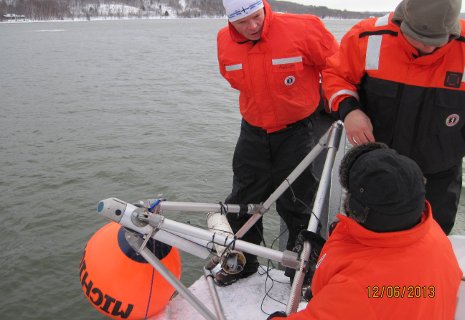 GLRC staff Michael Abbott, Jamey Anderson and Colin Tyrrell prepare to deploy the under-ice observatory from the research center's long dock. The orange float kept the device upright as it sank to the bottom.