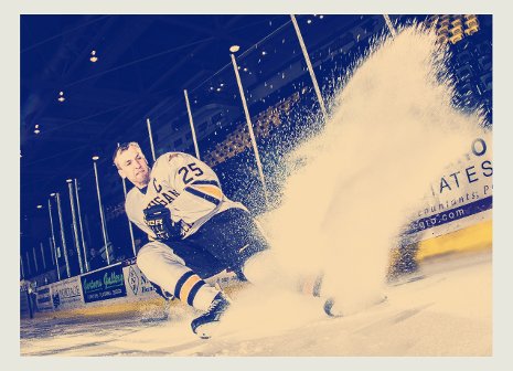 Hockey player spraying snow while stopping on the ice.