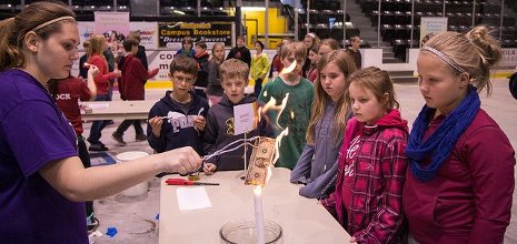 A high school student trained by Mind Trekkers shows rapt elementary school children that money really doesn't burn--if you soak it in an alcohol-water solution before setting it afire.
