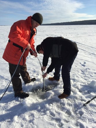 Researchers feeding cords through a hole in the ice.