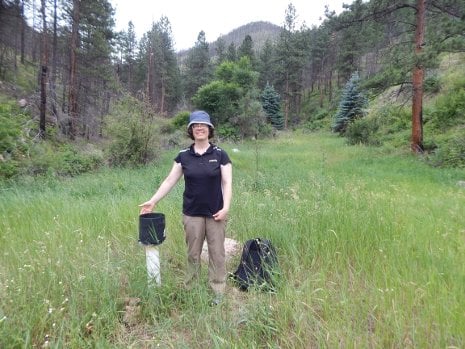 Mary Ellen Miller, a research scientist at the Michigan Tech Research Institute, stands next to a tipping bucket gauge at the High Park burn area in Colorado. 