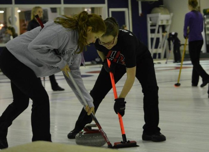 Alexis Schroeder (right) and a teammate sweep the ice to help direct the stone.
