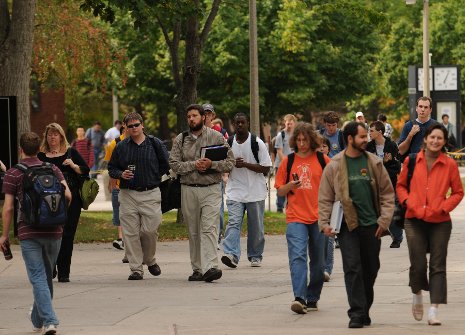 Students, faculty and staff walk across the Michigan Tech campus. 
