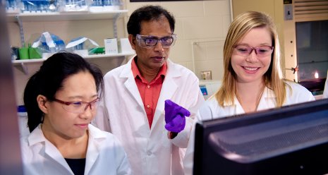 Tarun Dam, center, goes over research with PhD candidates Ni Fan, left and Melanie Talaga right in a lab at Michigan Tech.