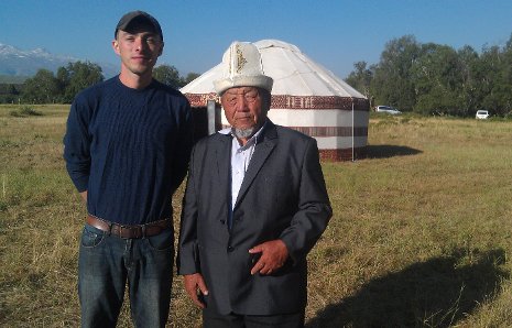 Cole Bedford, left, with a community member wearing a kalpak, traditional Kyrgyz headwear, standing in front of a Kyrgyz yurt.  
