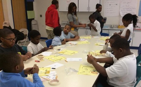 Michigan Tech student Rebecca Spencer, standing center in grey polo shirt, is seen working with Detroit school children in March of 2014. Once again this year members of Michigan Tech's chapter of the National Society of Black Engineers will spend spring break working with Detroit youth.