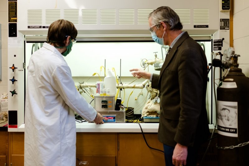 two people stand in front of a chemistry hood