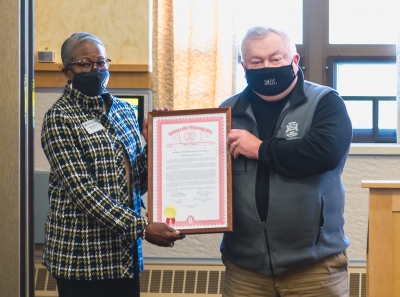 Two people hold a framed document between them.