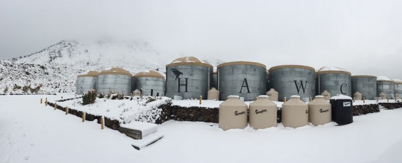 The cylindrical light detectors at HAWC, with snow covering the ground and the hillside in the background.