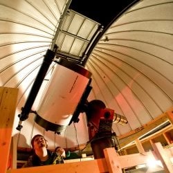 Student sits and looks through the telescope