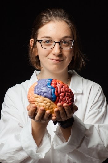 Pre-health student in lab coat holding a model of a brain