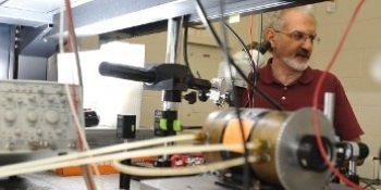 Miguel Levy, professor, stands behind nano equipment making adjustments