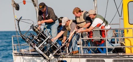 Researchers drop an underwater probe off of a boat.