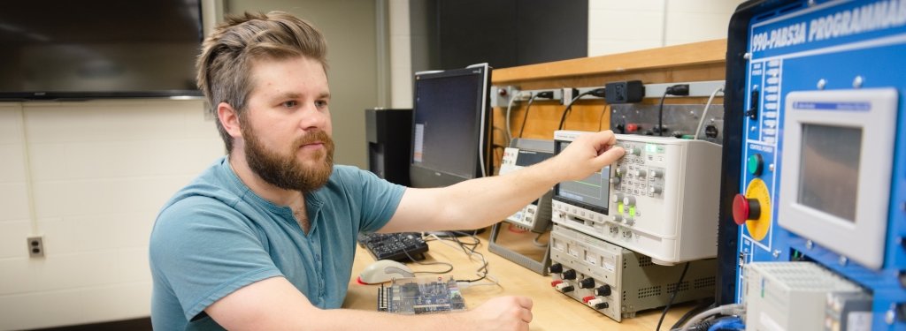Student operates an oscilloscope and programmable logic controller. 