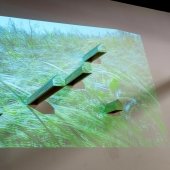 Digital grass projected on a screen with columns protruding.