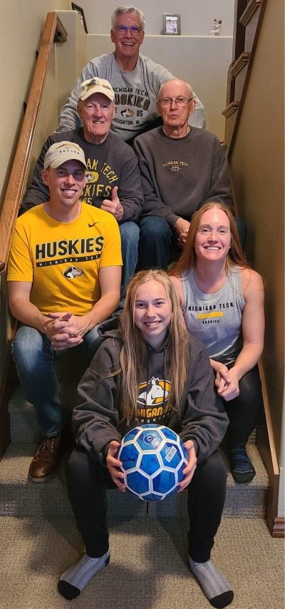 Three generations of Michigan Tech Huskies pose sitting on stairsteps, the oldest at the top and the youngest, who starts school in the fall, at the bottom.