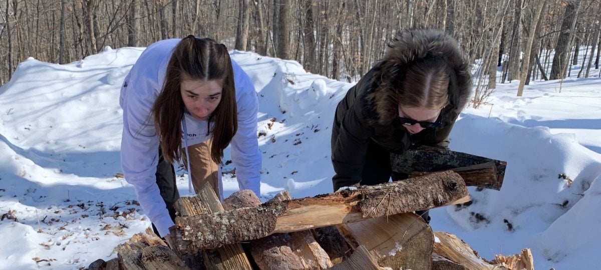 Claire and Vanessa stack firewood to be used at camp
