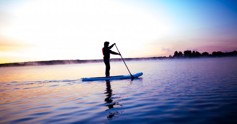 Person paddle boarding in the sunset.