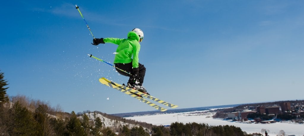 Skier in air with the Michigan Tech campus in the background.