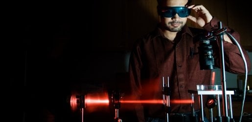 Student looking at a equipment that is shining a laser beam.