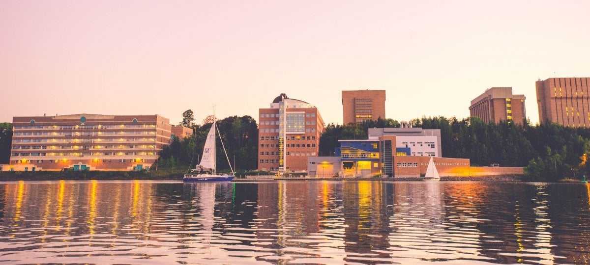 A view of campus from across the waterway with sailboats.