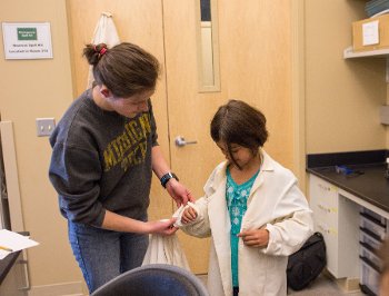 Cat Vendlinski gets help rolling up her sleeves to get ready for a lab lesson.