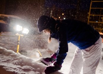 A female student irons the side of a snow statue while snow falls.