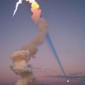 The plume of a rocket launch and the moon.