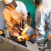 people in safety gear pour molten metal