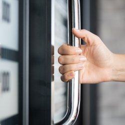 hand cripping a silver handhold on the door of a commuter vehicle with blurred background