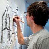 Student works on a pencil drawing on the studio wall.