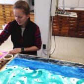 Student working on a painting of swirls and water.