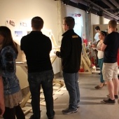 Students looking at their work on the wall while other students look on inside gallery b