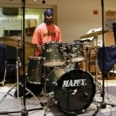 Student sitting behind a drum set in the Instrumental Rehearsal Room.
