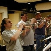 Side view of four people standing playing trumpets in the Instrumental Rehearsal Room.
