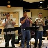 Front view of four people standing playing trumpets in the Instrumental Rehearsal Room.