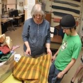 Faculty M.C. Friedrich showing a piece of fabric to a student.