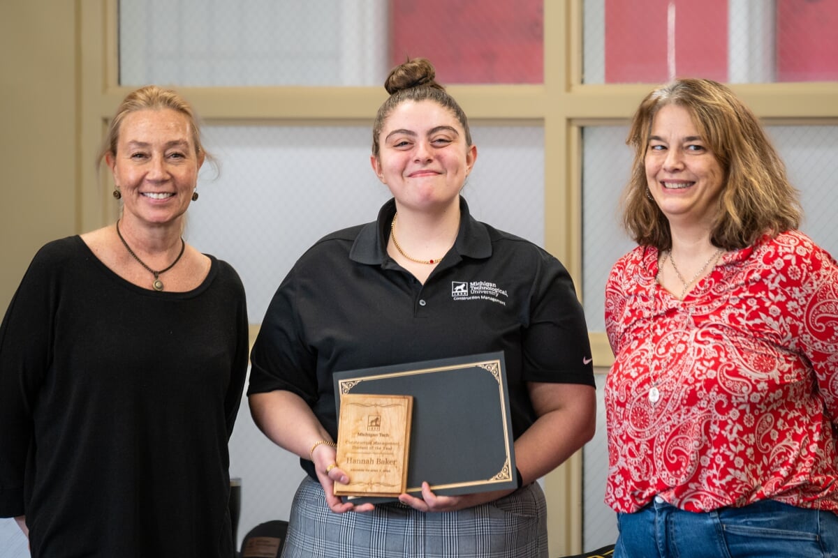 A student holding their award with two faculty members. From left to right - Kerri Sleeman, Hannah Baker, Jen Miller
