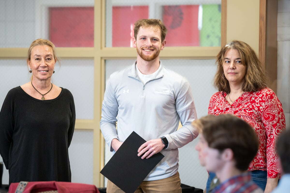 A student holding their award with two faculty members. From left to right - Kerri Sleeman, Matthew Zimmerman, Jen Miller