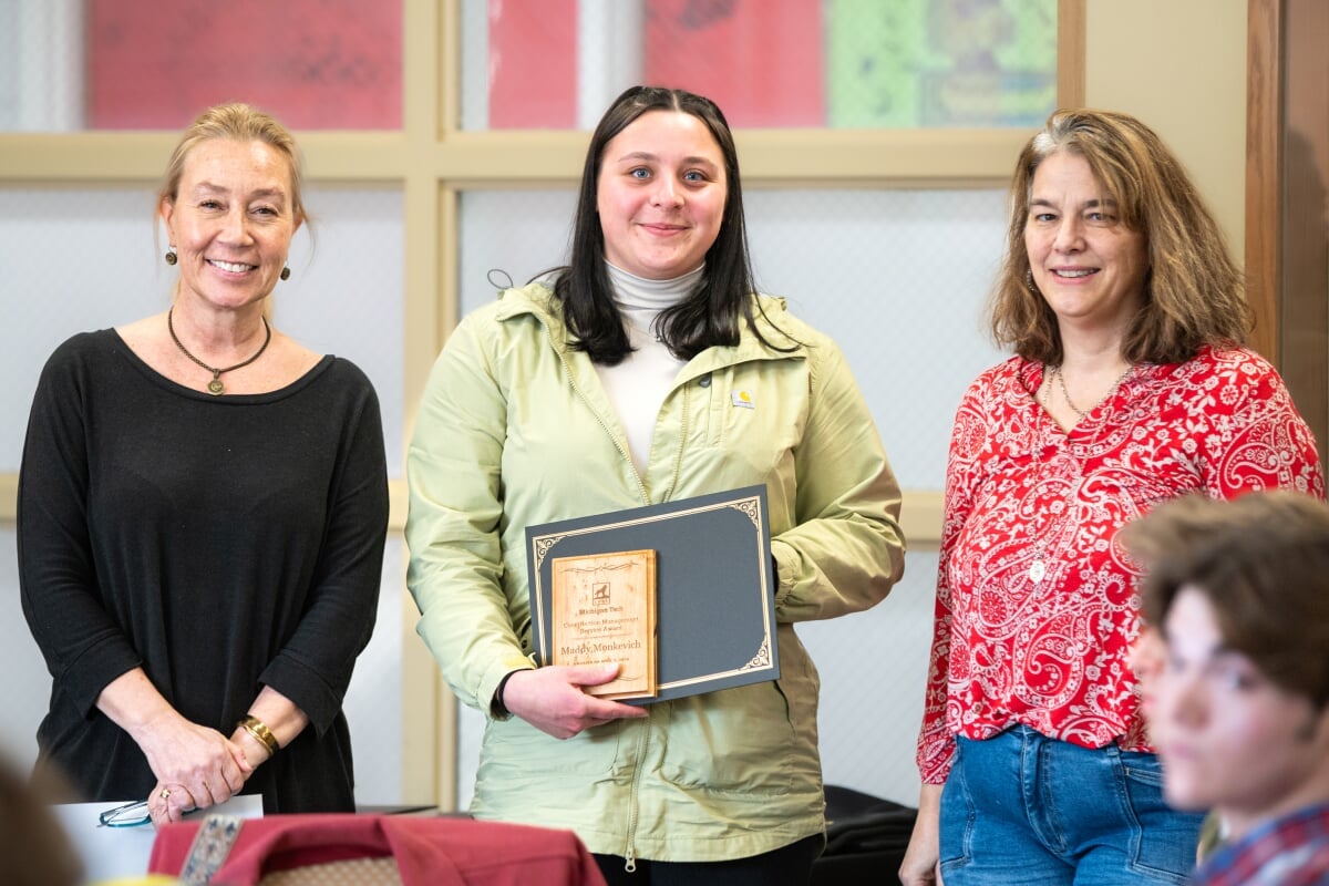 A student holding their award with two faculty members. From left to right - Kerri Sleeman, Maddy Monkevich, Jen Miller