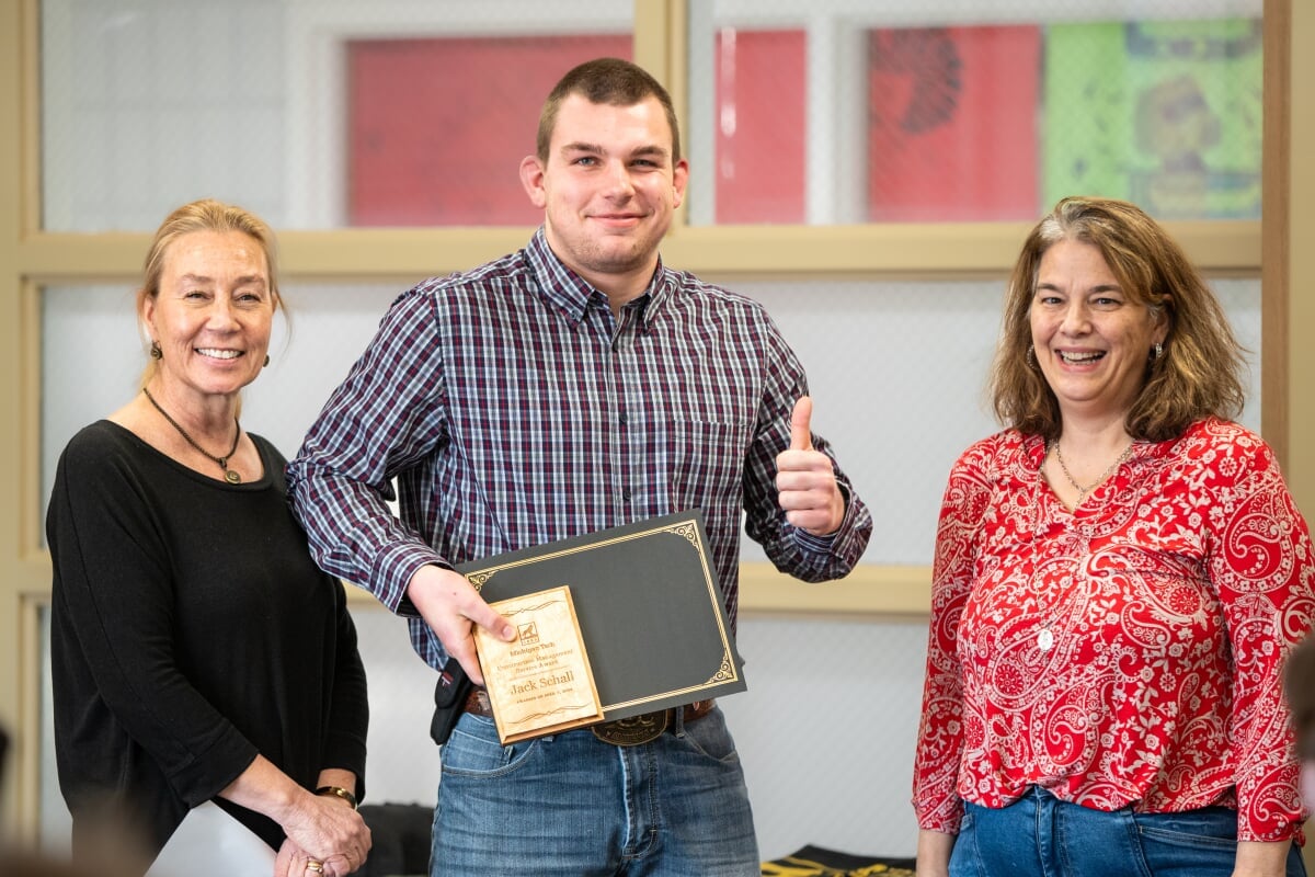 A student holding their award with two faculty members. From left to right - Kerri Sleeman, Jack Schall, Jen Miller