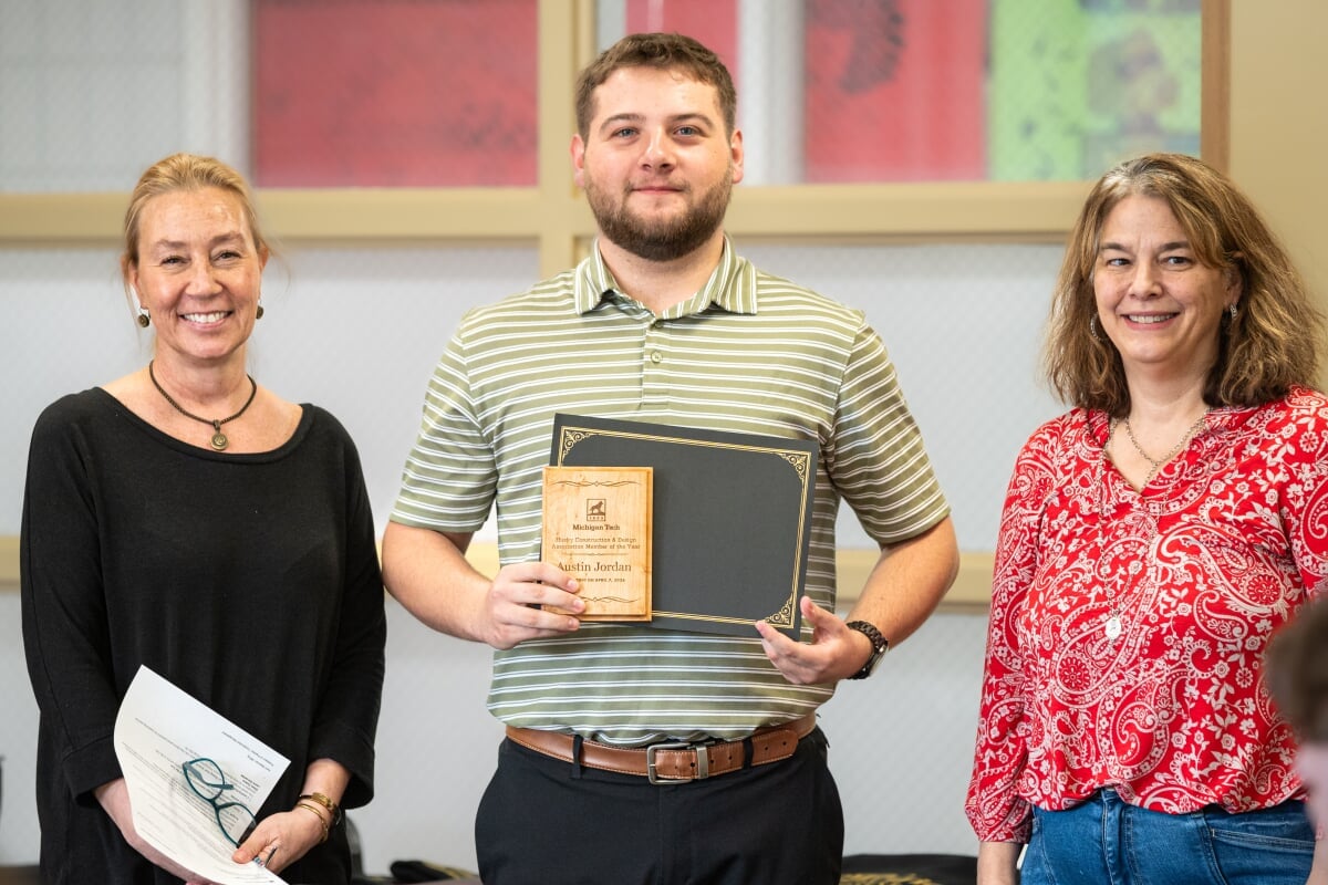 A student holding their award with two faculty members. From left to right - Kerri Sleeman, Austin Jordan, Jen Miller